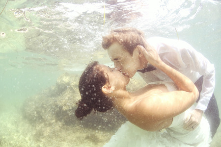 Bride and groom kissing underwaterの写真素材