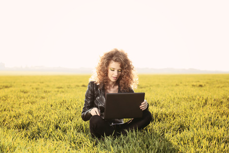 Beautiful women with laptop in green fieldの写真素材