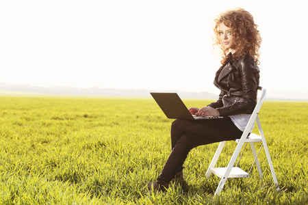Beautiful women with laptop in green fieldの写真素材