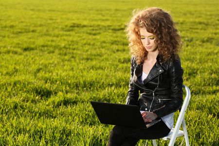 Beautiful women with laptop in green fieldの写真素材