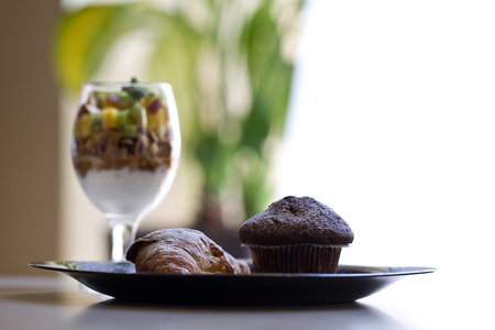 Delicious muffin and croissant with fruits and cereal yogurt;