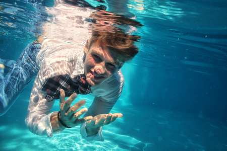 Sexy guy diving in pool underwaterの写真素材