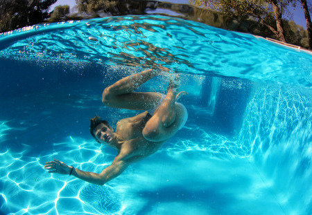 Sexy guy diving in pool underwaterの写真素材
