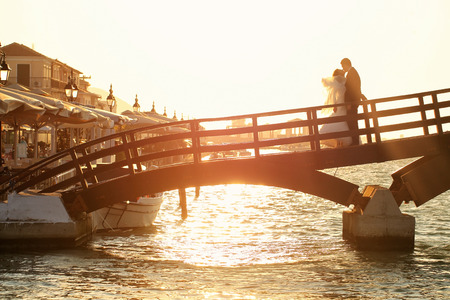 groom and bride kissing on a bridge at sunsetの写真素材