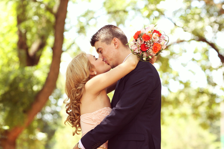 Beautiful bride and groom embracing in the parkの写真素材