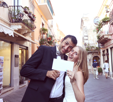 Joyful bride and groom holding a piece of paperの写真素材