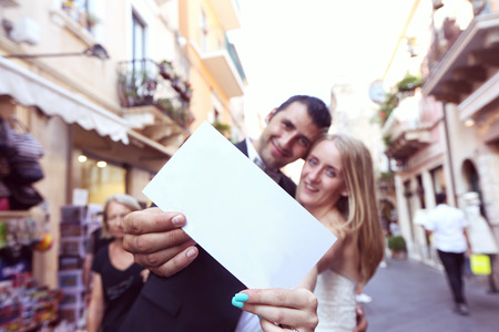Joyful bride and groom holding a piece of paperの写真素材