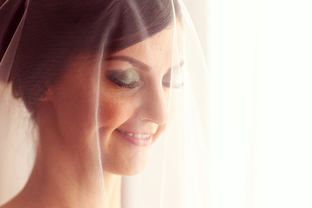 Portrait of beautiful bride with veil smiling on wedding dayの写真素材