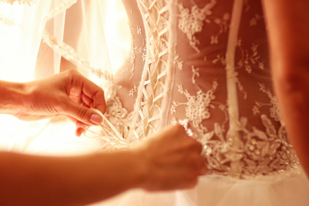 Bride getting ready for wedding helped with the corsetの写真素材
