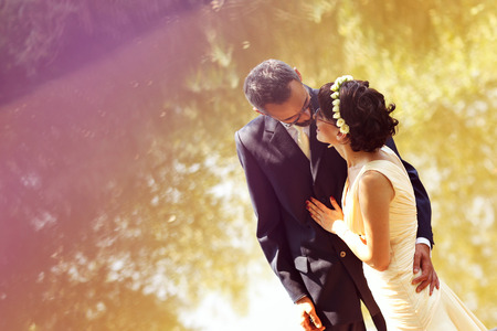 Beautiful bride and groom embracing and kissing in fieldの写真素材