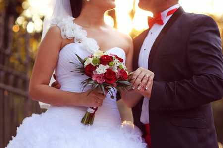 Beautiful bride and groom embracing and holding flower bouquetの写真素材