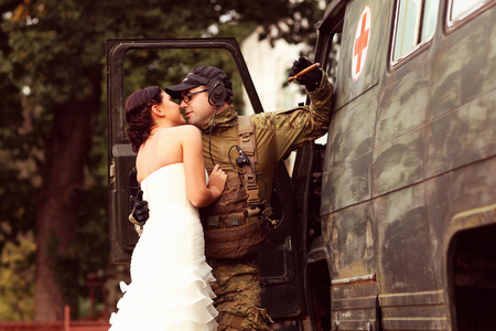 Bride embracing with groom in army suitの写真素材