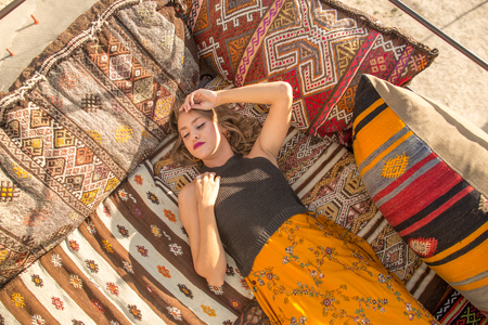 A beautiful young woman sits on one of the Cappadocia roof. Romantic scene.の写真素材