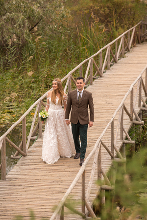 Beautiful wedding couple posing on wooden bridgeの写真素材