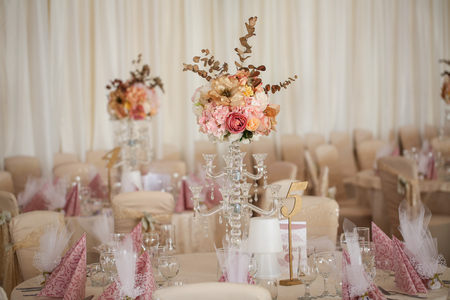 Beautiful white round table at the restaurant. Wedding reception day. Champagne and floral compositionの写真素材