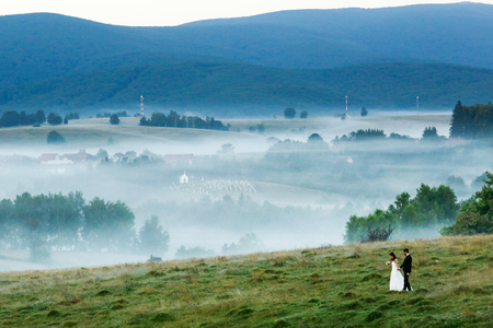 Beautiful wedding couple posing upon hills on fogの写真素材