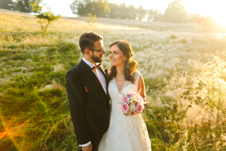 Beautiful wedding couple, bride and groom posing on wheat fieldの写真素材