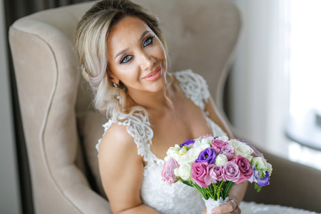 Beautiful blonde bride posing in luxury roomの写真素材