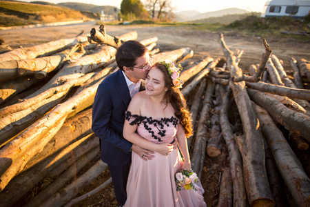 Beautiful young wedding couple, bride and groom posing near wooden cutの写真素材