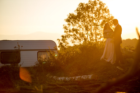 Beautiful wedding couple posing in suset near wooden cutの写真素材