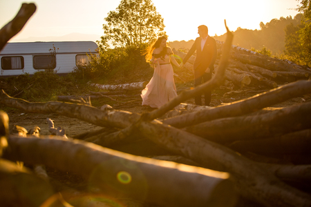 Beautiful wedding couple posing in suset near wooden cutの写真素材