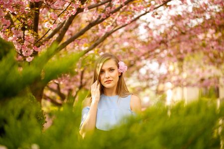Outdoor fashion photo of young beautiful lady surrounded spring leavesの写真素材