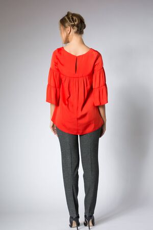 Beautiful blonde model posing in red blouse and gray pantsの写真素材