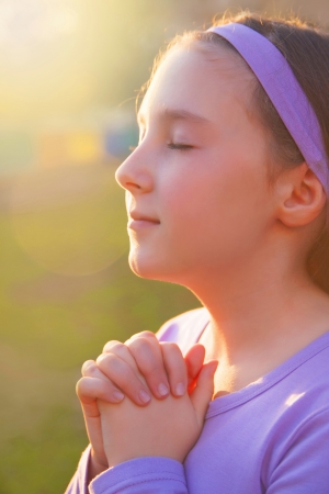 Girl praying with eyes closed et the sunsetの写真素材