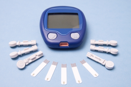 Glucometer with lancetes and test strips on Blue Backgroundの写真素材