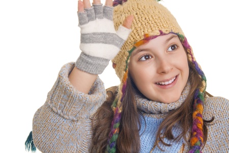 Beautiful young girl in warm winter clothes smiles and waves isolated on whiteの写真素材
