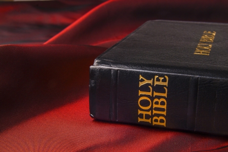 Black leather bible cover written with golden letters on red fabricの写真素材