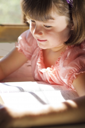 Beautiful Girl Reading Holy Bible. Sitting on a tableの写真素材