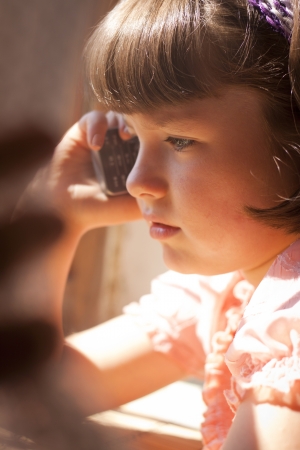 Little girl talking on cell phone. Beautiful  sunlightの写真素材