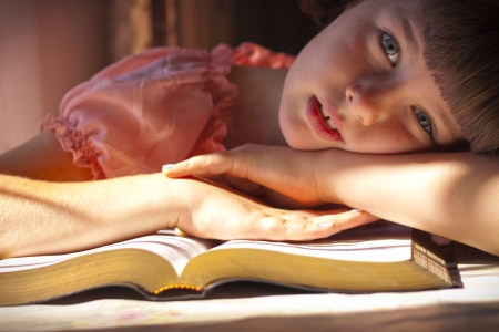 Beautiful Girl Reading Holy Bible. Sitting on a tableの写真素材