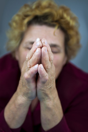 Senior woman praying  Blurred backgroundの写真素材