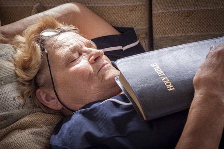 Adult woman fell asleep with a bible in her handsの写真素材