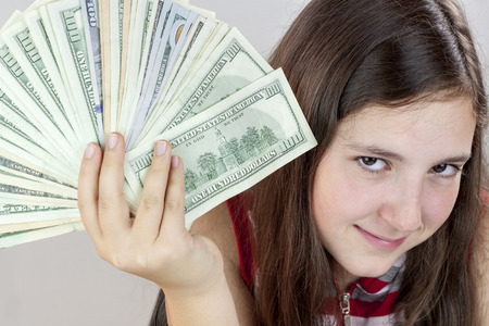 Beautiful teen girl holding US dollars. Face expressionの写真素材