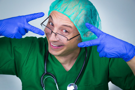 Doctor surgeon showing scissors with his hands. Funny photoの写真素材