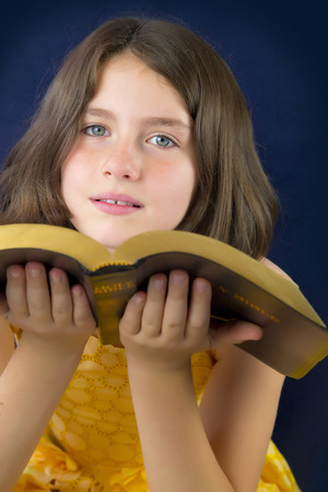 Portrait of beautiful little girl holding Holy Bible. Open bibleの写真素材
