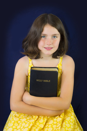 Portrait of beautiful little girl holding Holy Bible. Closed bibleの写真素材