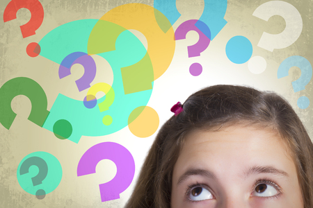 Teenage girl looking to multitude of colorful guestion marks expressing dilemma and hesitation. Grunge background.の写真素材