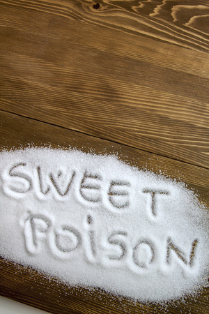 SWEET POISON written on sugar on brown wooden table. Health conceptの写真素材