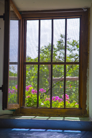 Open window with metal bars, bright summer day outdoors - darkness indoorsの写真素材