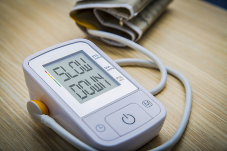 Digital blood pressure meter with warning message SLOW DOWN on the monitor. Health hazard conceptの写真素材