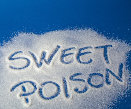 Sugar on a blue background with warning message SWEET POISON written on it. Health concept. Diabetes hazardの写真素材