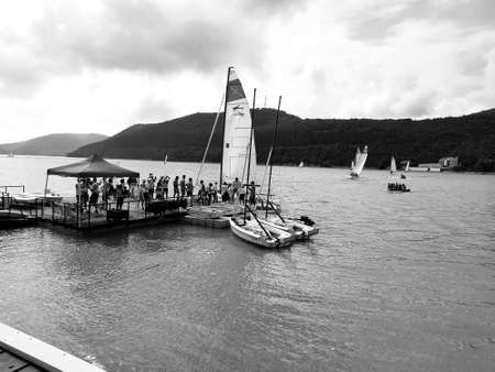 September 27, 2020 Russia Abrau-Durso. Competitions of small yachts on lake Abrau. The yacht docked at the pier for a change of crew, after passing the next stage.Black and white photo.のeditorial素材