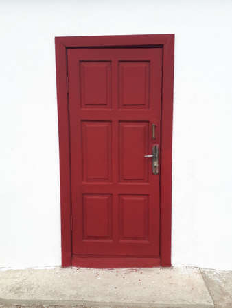 A wooden door painted red against a white wall.の写真素材