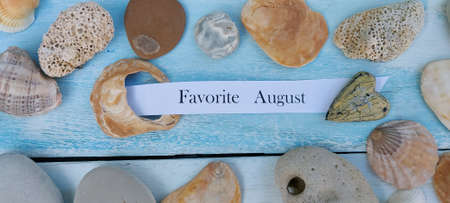 Sea stones and seashells on a wooden blue table background. With the inscription "favorite August".の写真素材