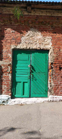 Old green gate in a brick barn. Construction, design.の写真素材
