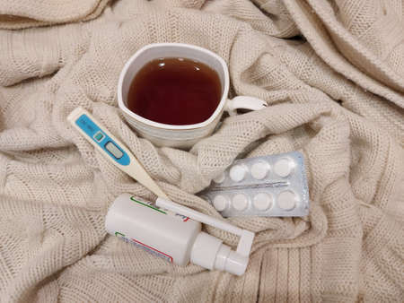 November 22, 2020 Novorossiysk Russia. Health: tea with rose hips, analgin tablets, throat spray and a thermometer against the background of a knitted blanket.のeditorial素材